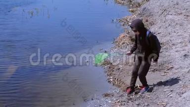 男孩正在用蝴蝶网在河上放青蛙和鱼。